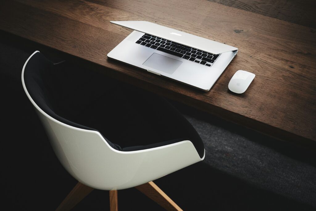 A desk with a laptop on it, and a chair