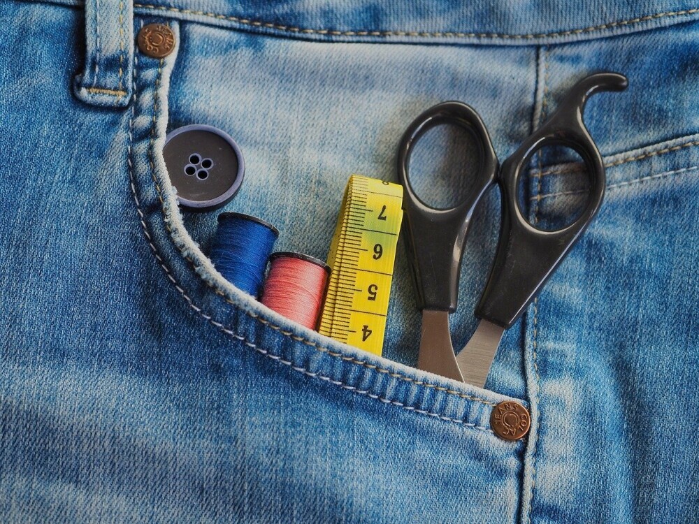 A pocket with a pair of scissors, a measuring tape, and cotton sticking out.