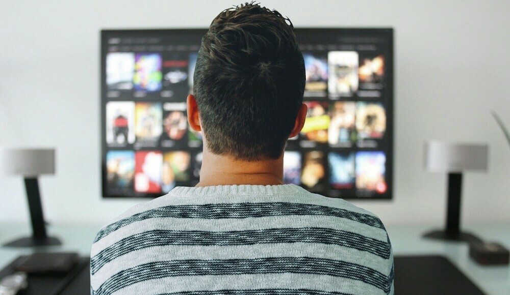 The back of someone's head, looking at a computer screen showing videos