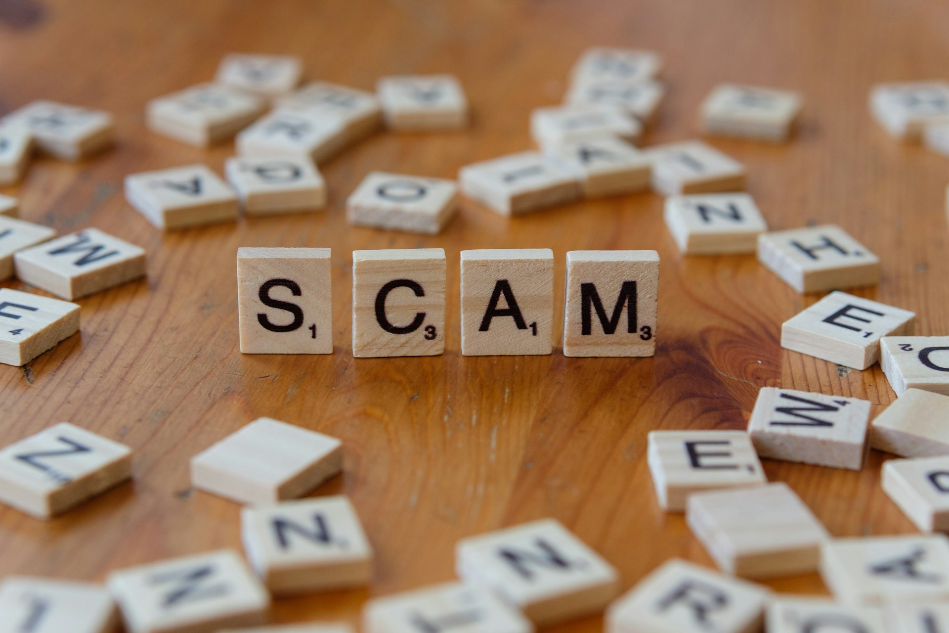 Scrabble letters that spell the word 'SCAM'