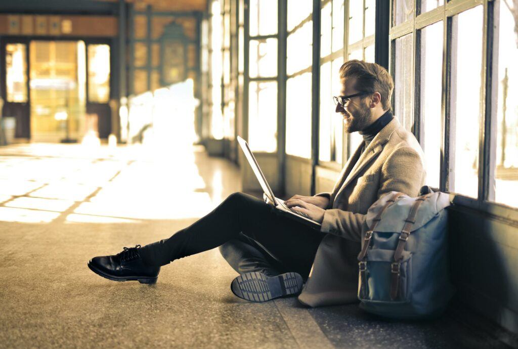 A man sitting on the floor, working at a laptop