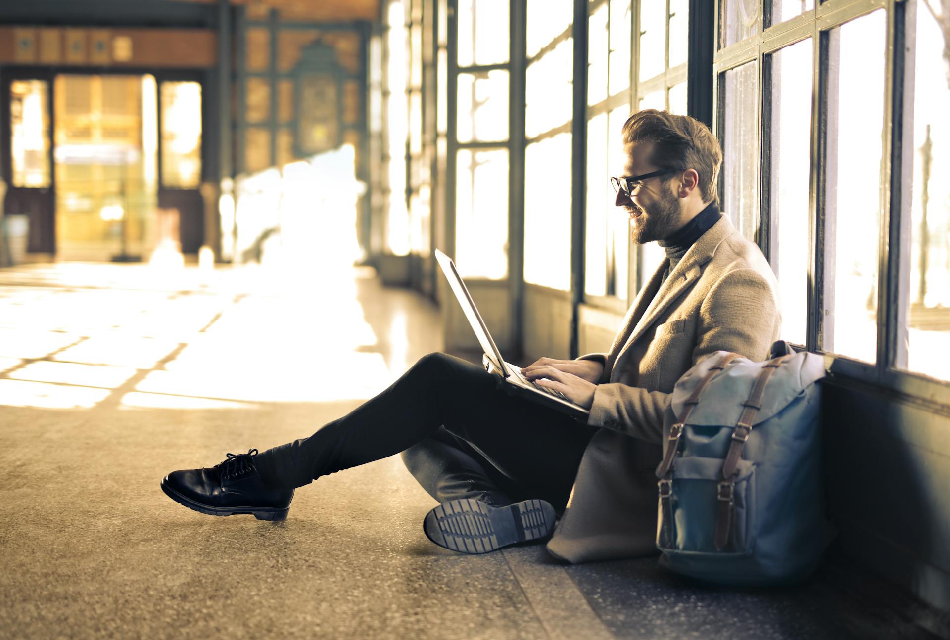 A man sitting on the floor, working at a laptop